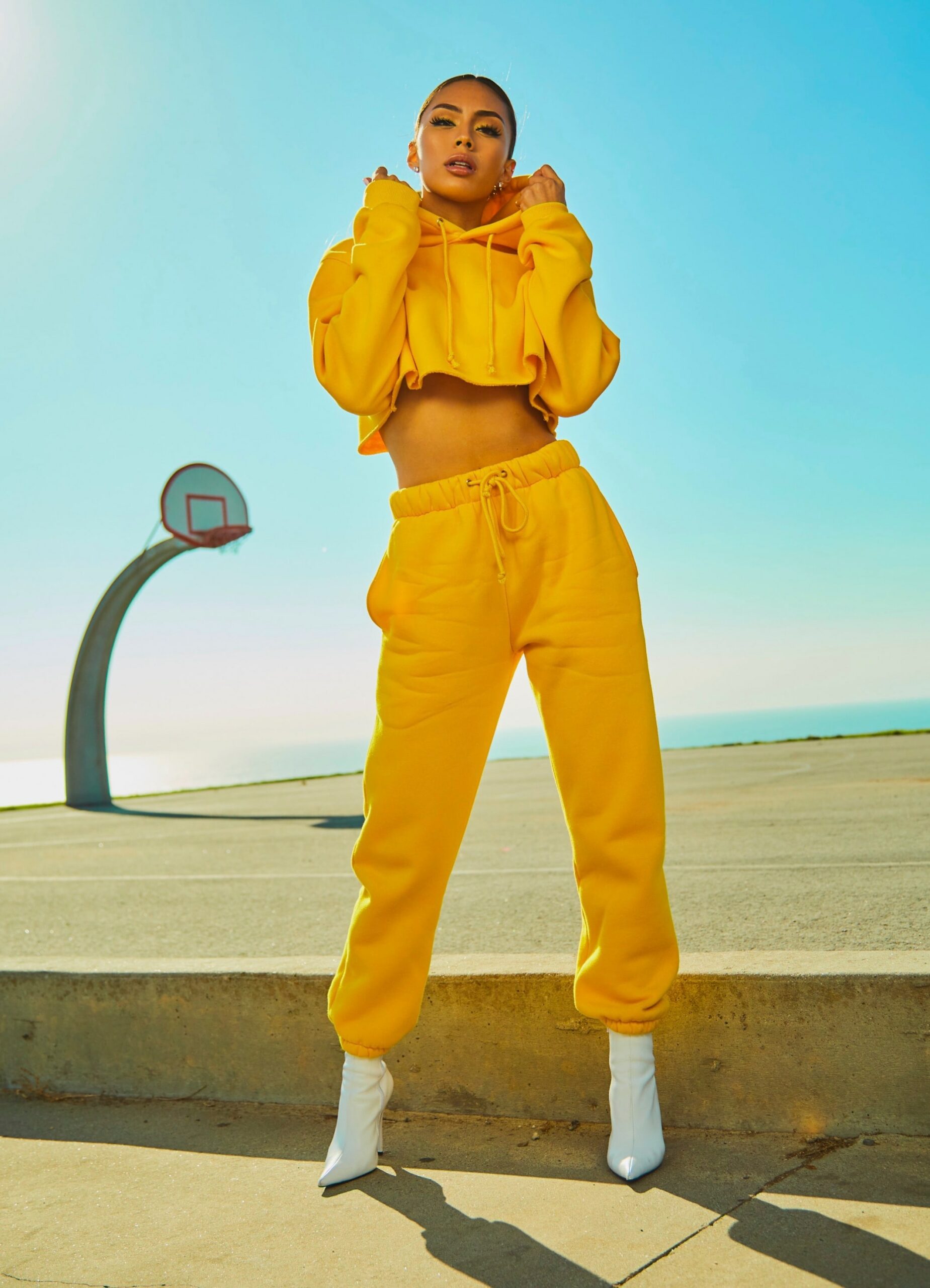 Model wearing a yellow sweatsuit with white high heals. 