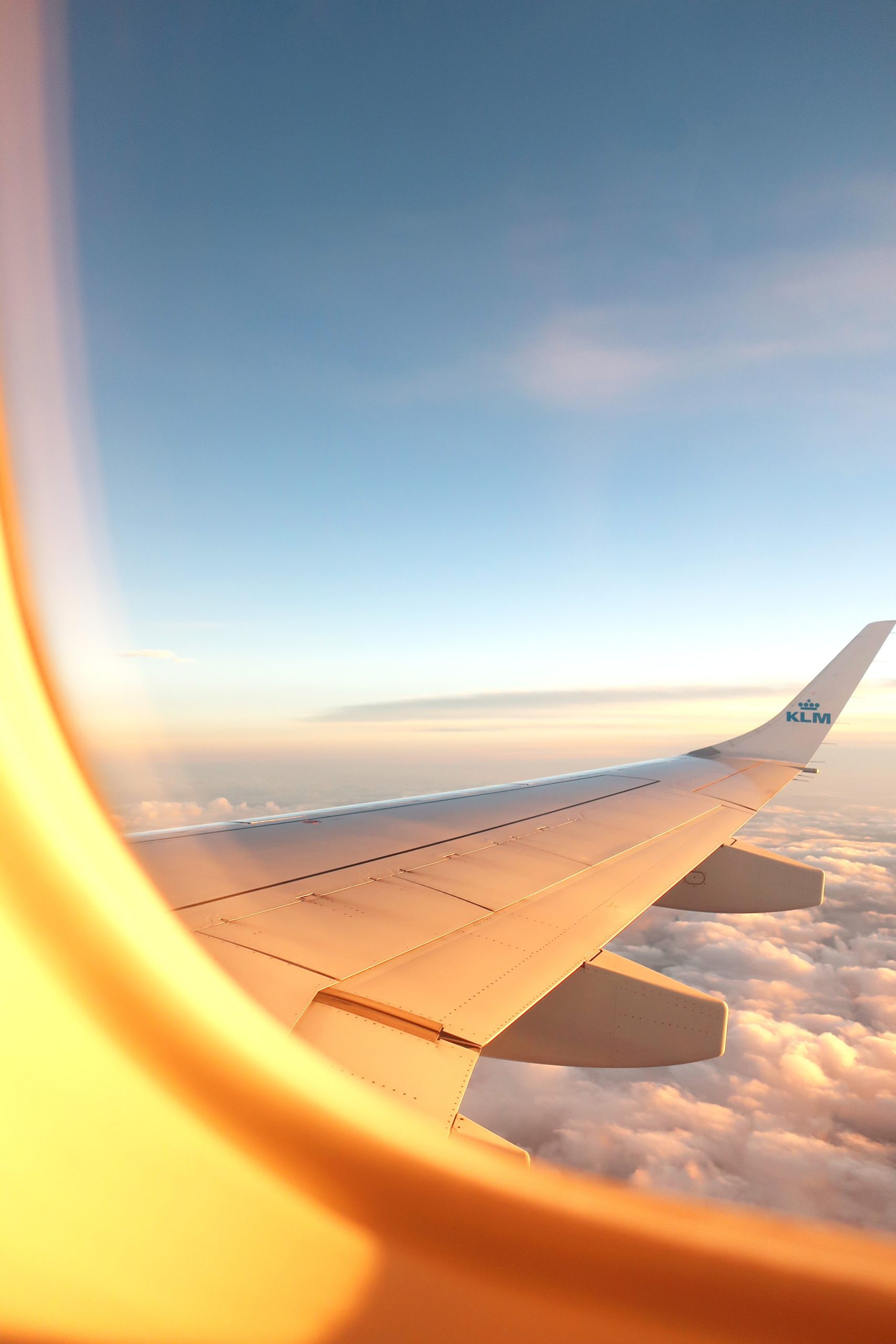 Window of an airplane looking out at the wing on the plane in the sky.
