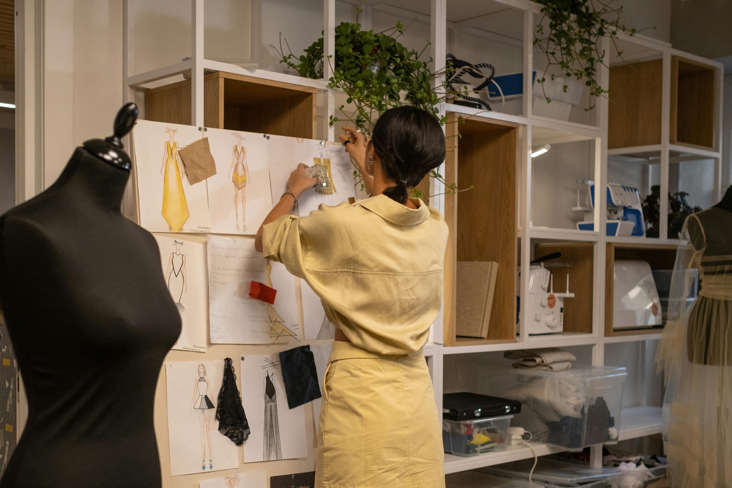 A women in a fashion job pinning designs on a board